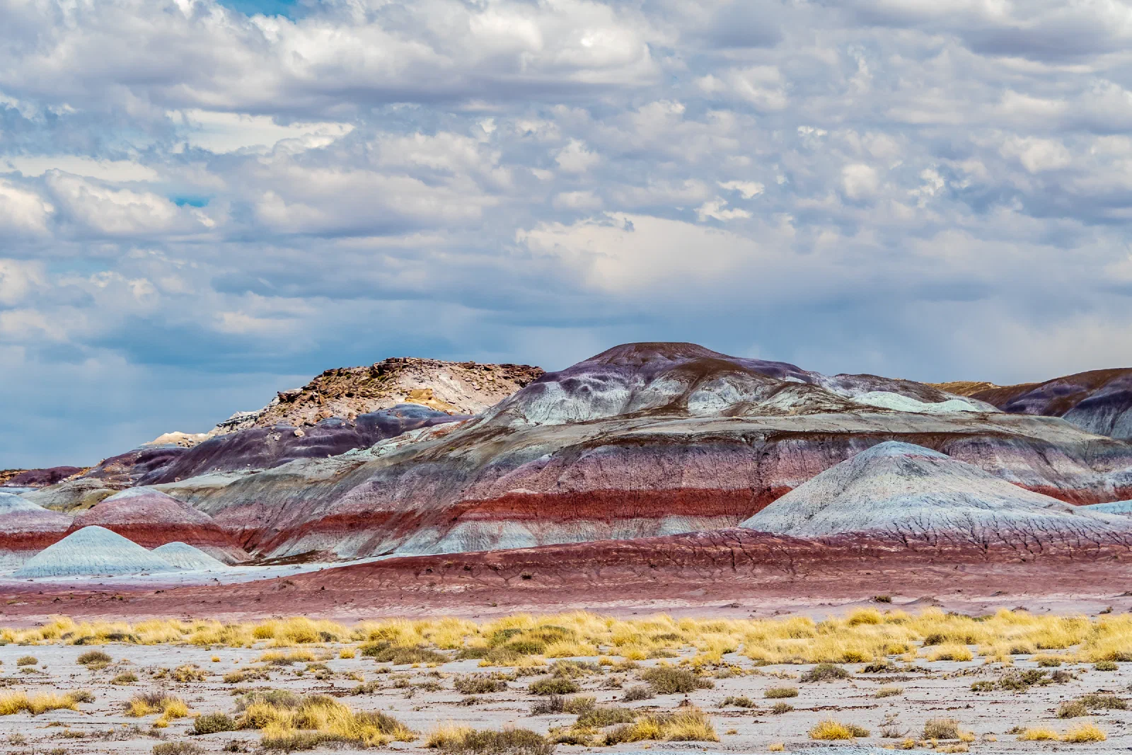 Colorful layered hills beneath a cloud-filled sky in Petrified Forest National Park